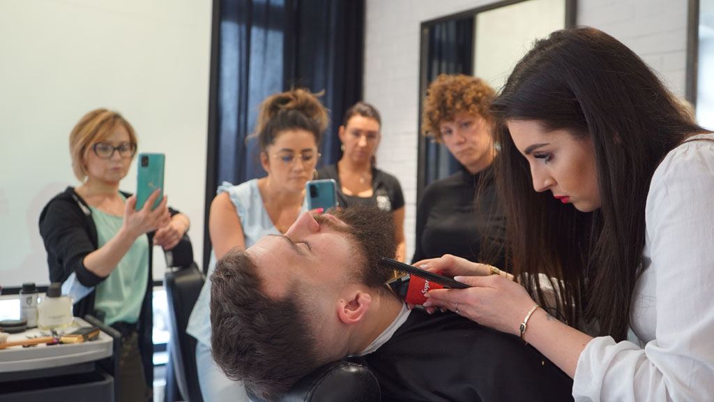 fryzjerka strzyże brodę mężczyzny podczas szkolenia