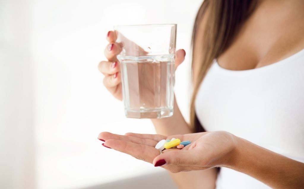 kobieta tabletki suplementy diety szklanka wody dekolt